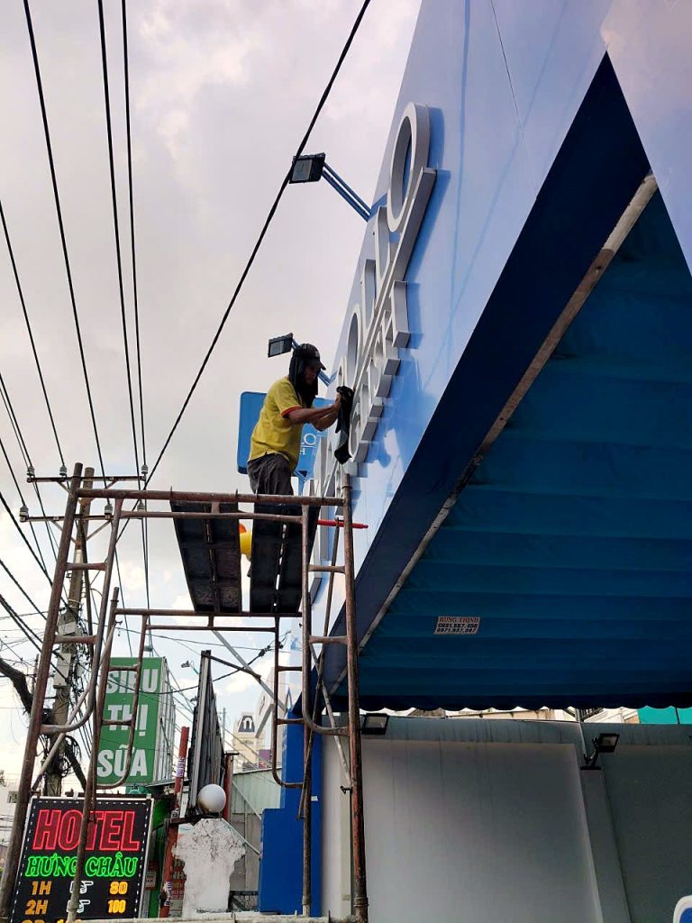 TECO crew working on English centre signage from scaffolding
