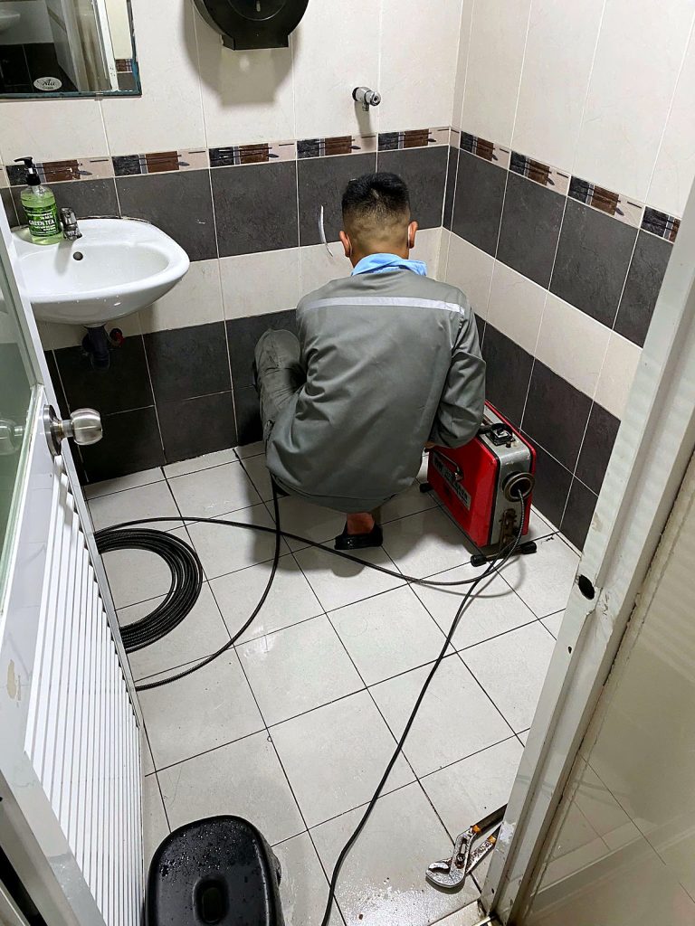 Clearing a blocked restroom drain with a drain-cleaning machine